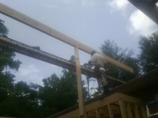Carpenter setting a ridge beam over a new addition frame — Ice Dam Removal by Roofing Brothers in Bellville