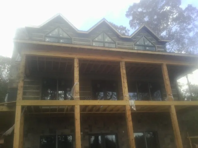 Dormers and porch framing on a large log home under construction — Roof Coating work by our crew in Bellville