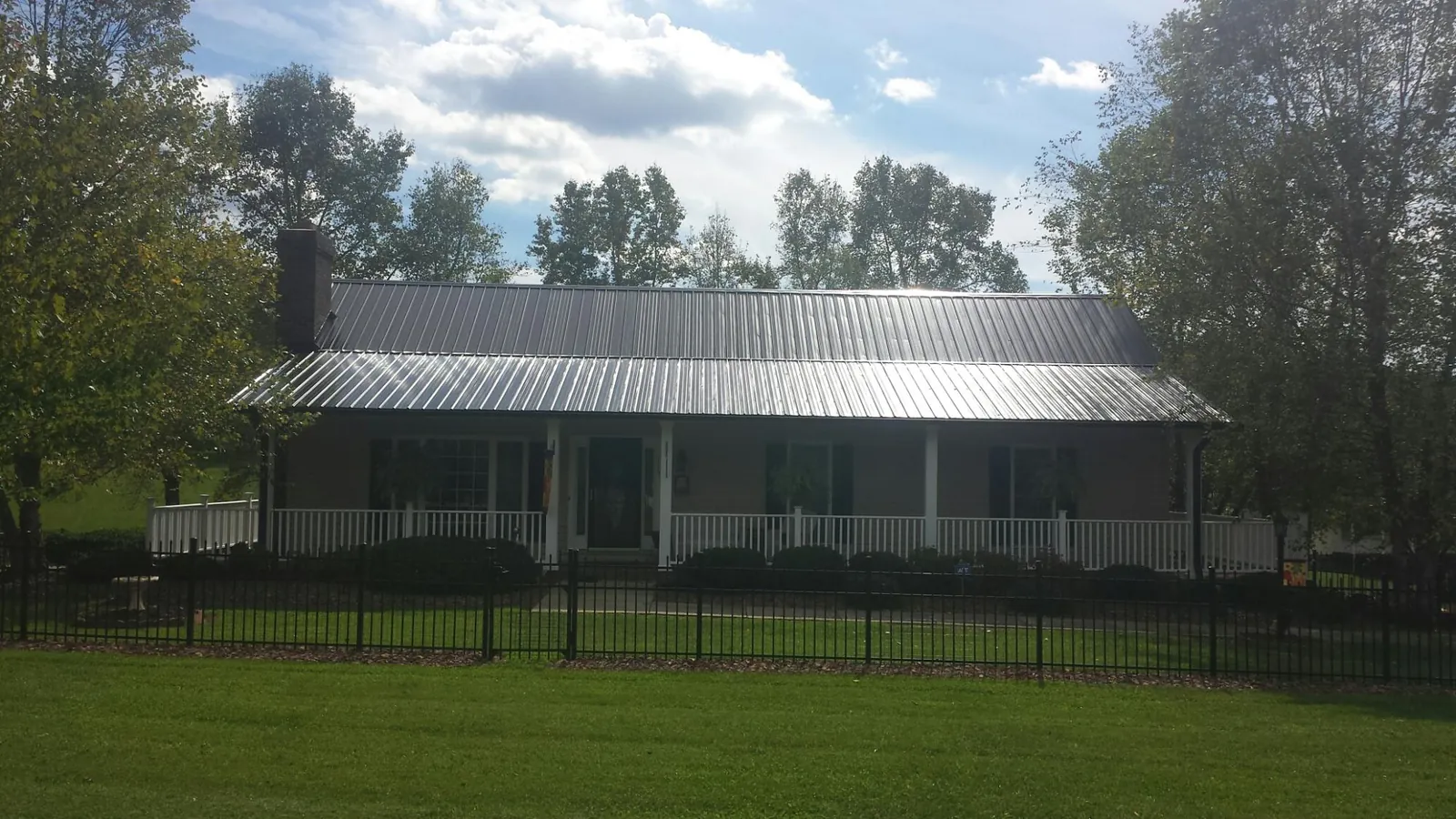 Gray metal roof on a brick ranch with a full width front porch — Gutter Guard Installation work by our crew in Bellville